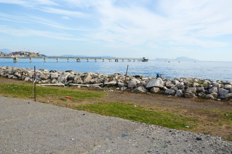 an empty road by the water has some rocks and grass