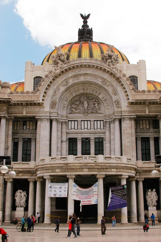 many people in front of an old building with gold domes