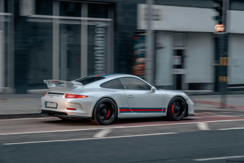 the porsche 911 is driving through a city street