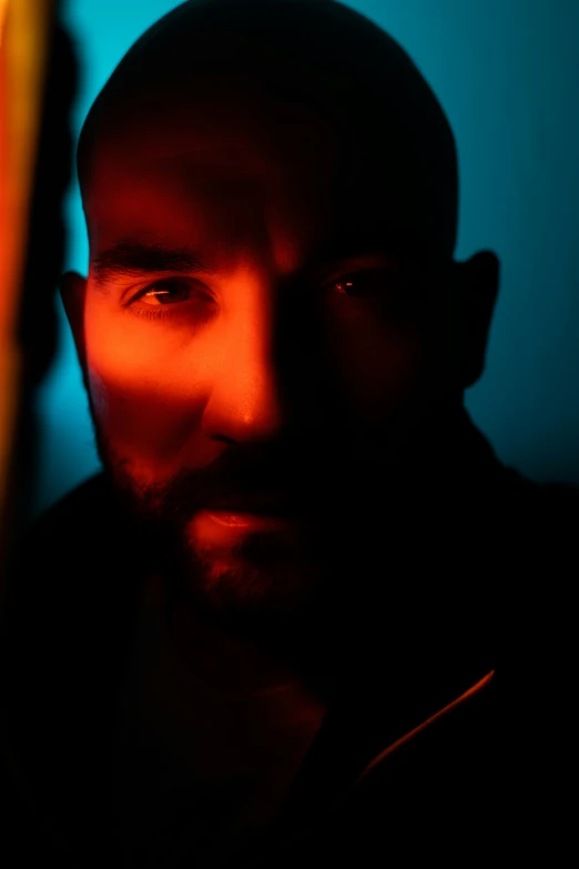 the man is staring up to the camera with red lighting behind him