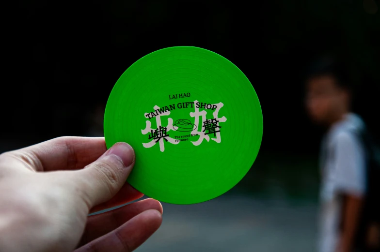 an orange frisbee with black and white writing is held in a persons hand