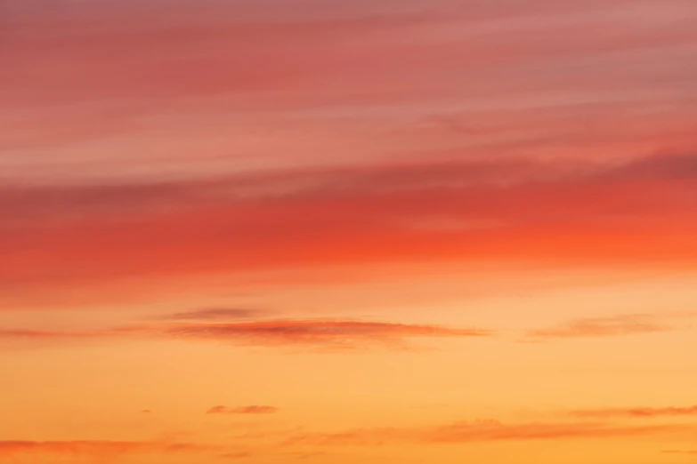 a plane flying in an orange and yellow sky