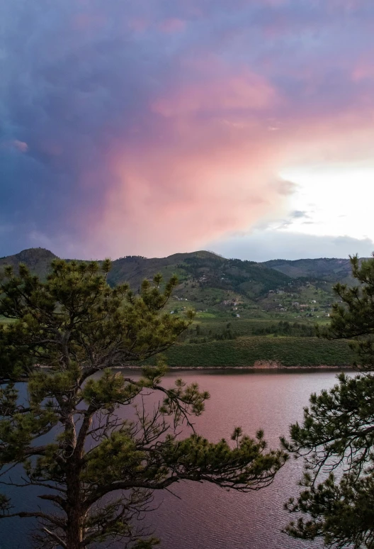 the pink clouds over the water are changing colors