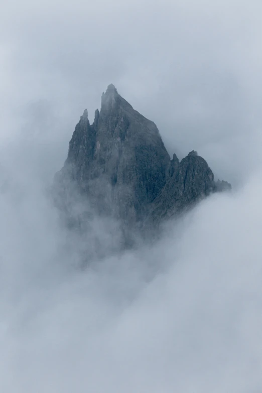 a mountain on top in the cloudy sky