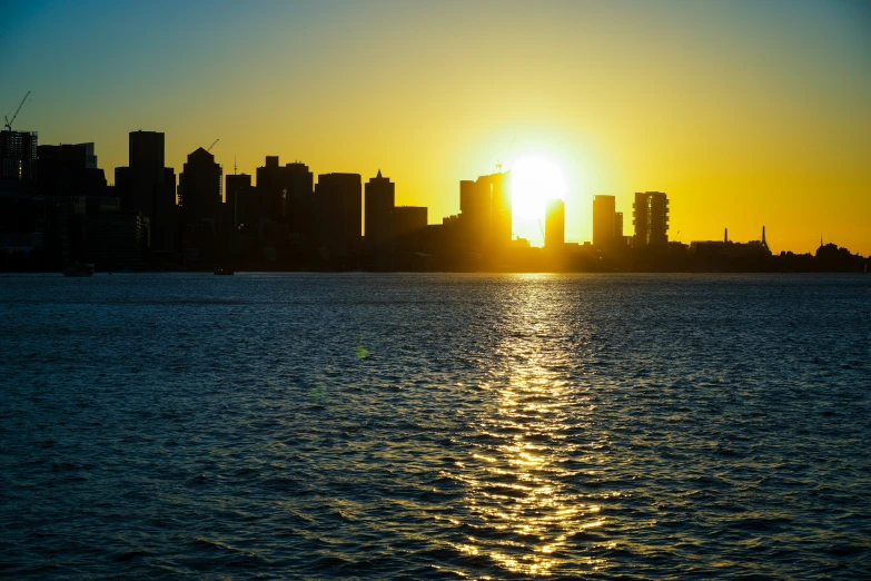 the sun rising over the city skyline, as seen from the ocean