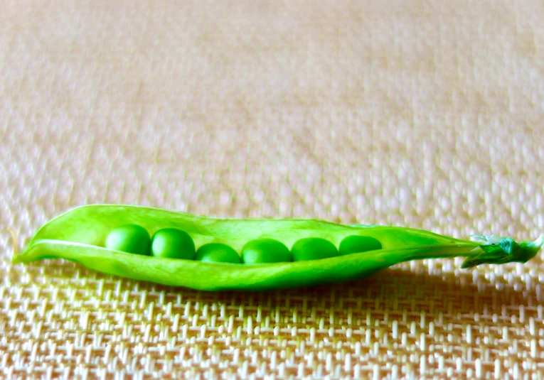 a pea and a peal on a tan cloth