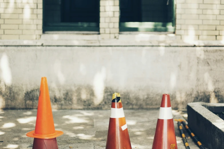 three cones are sitting in the concrete outside of a building