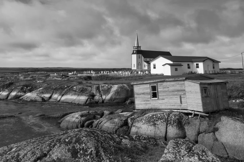 a lighthouse next to a rocky beach under a stormy sky