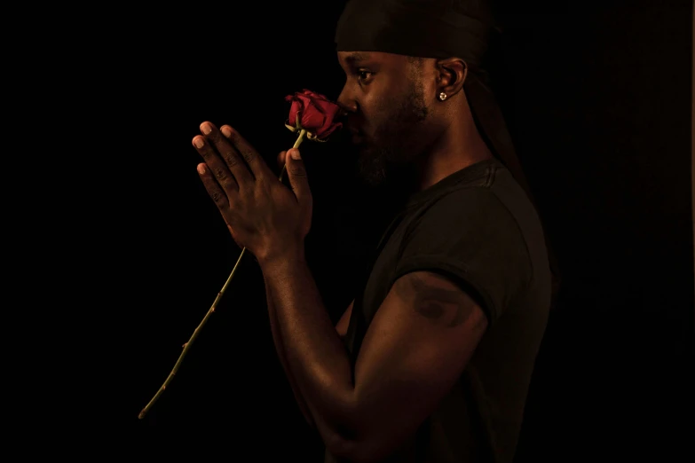 a man is holding up a rose to his chest