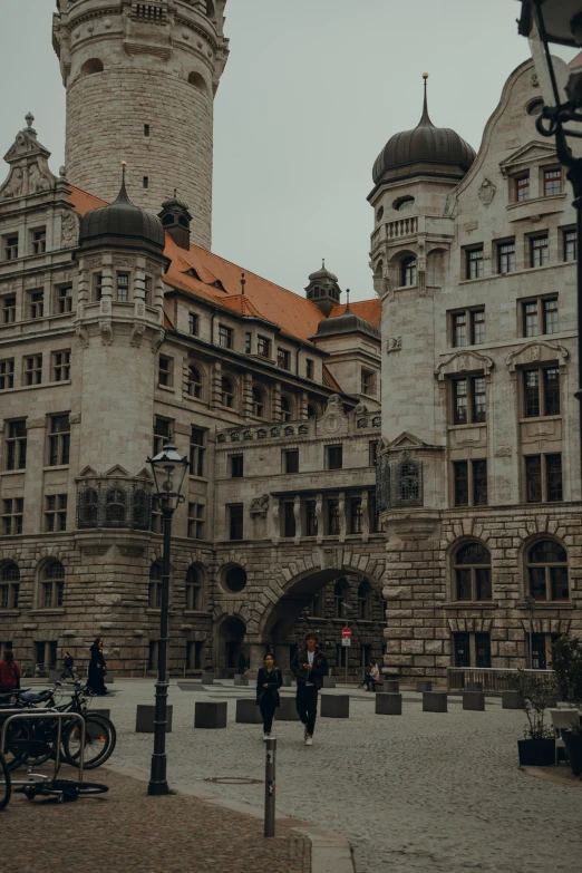 some people walking outside an old building with two clocks