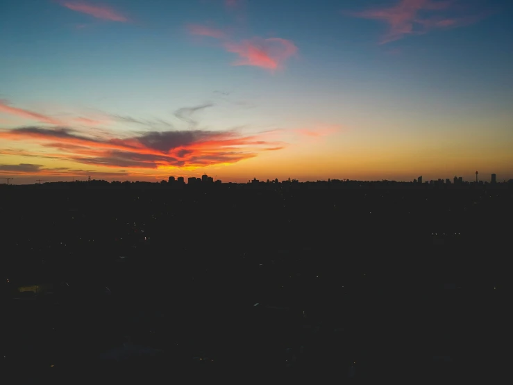 a sunset over some trees with a few clouds