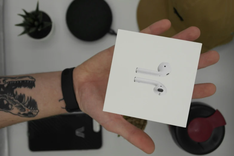 a person is holding a piece of white paper with an earbuds on it