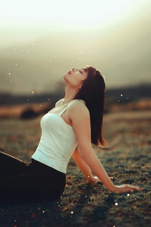 a girl sitting in the grass while looking up at soing