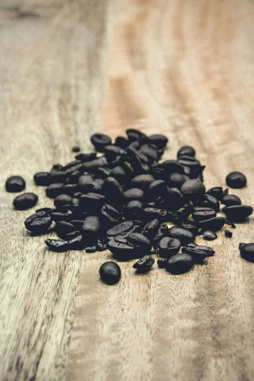 a pile of uncooked black beans are sitting on a wooden table