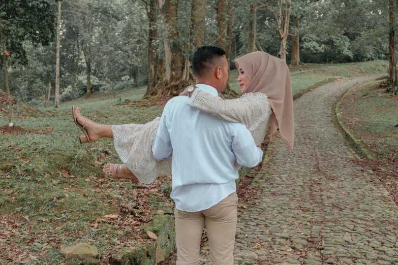an asian man carrying his pregnant wife up a path