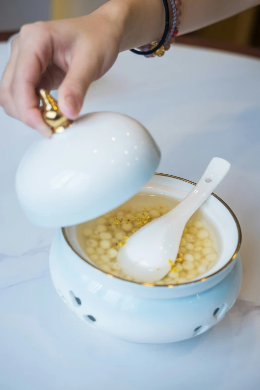 someone is pouring white liquid in a bowl with a white spoon