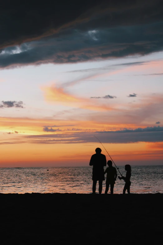 people are silhouetted on the beach while fishing