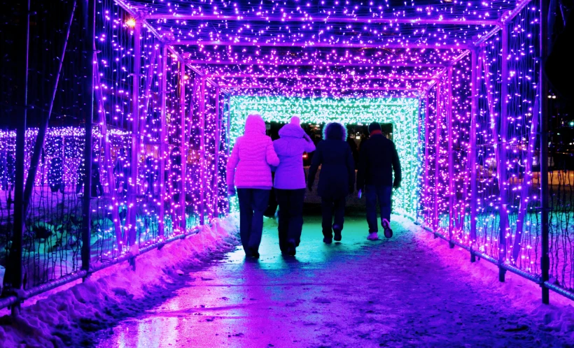 several people are walking down a lighted walkway