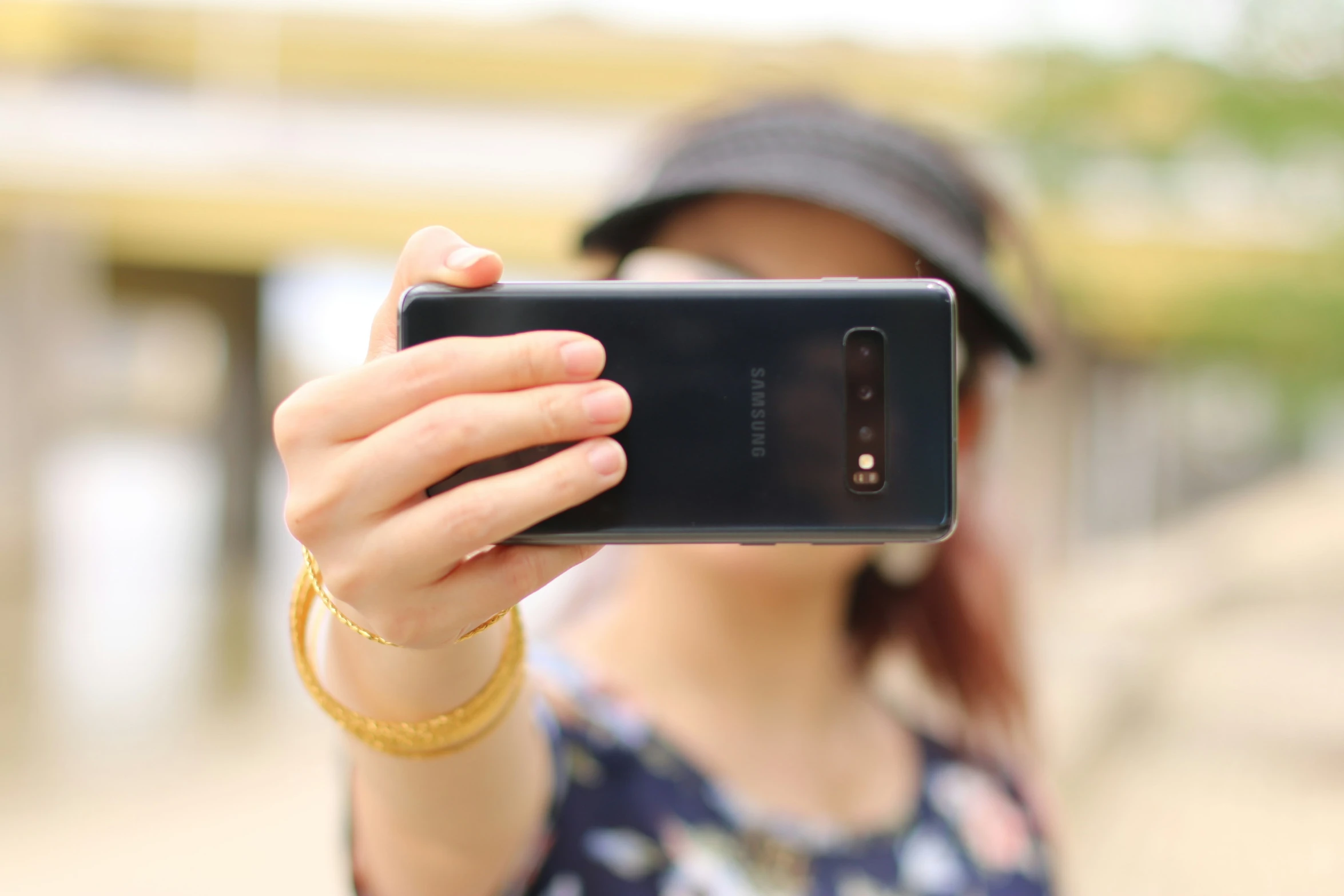 a woman in a hat holding onto a cell phone