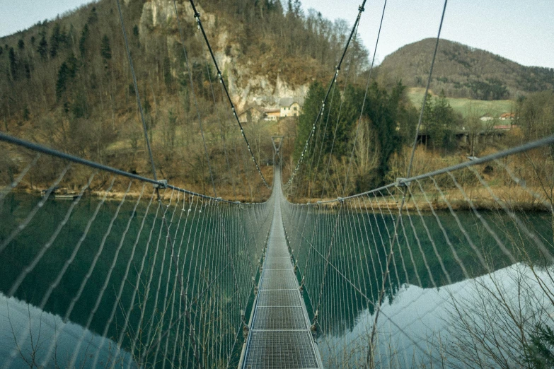 a suspension bridge near a mountain with a green valley