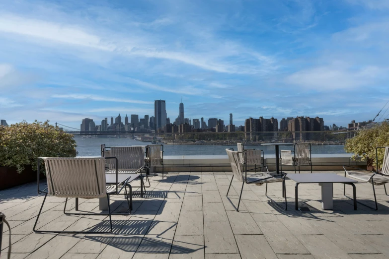 chairs and tables on a deck overlooking a city