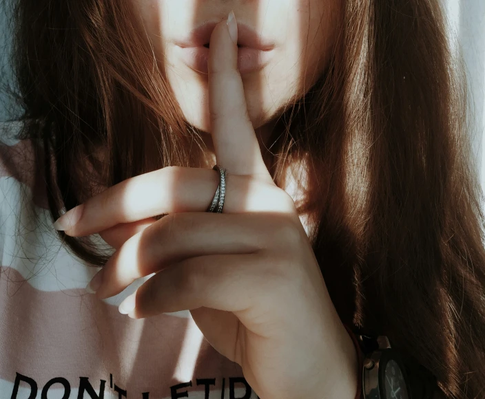 a girl holds her hands together to make a sign with both fingers