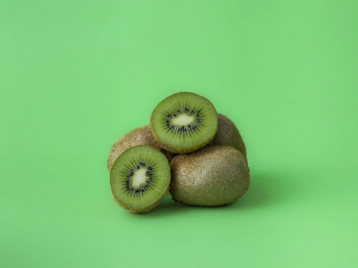 a group of kiwi fruit is displayed on a bright green background