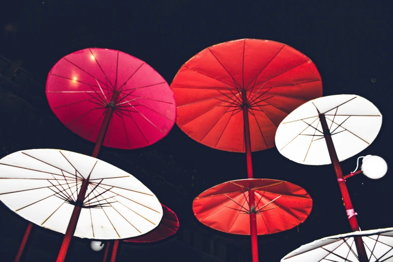 a bunch of umbrellas hanging up against a black background