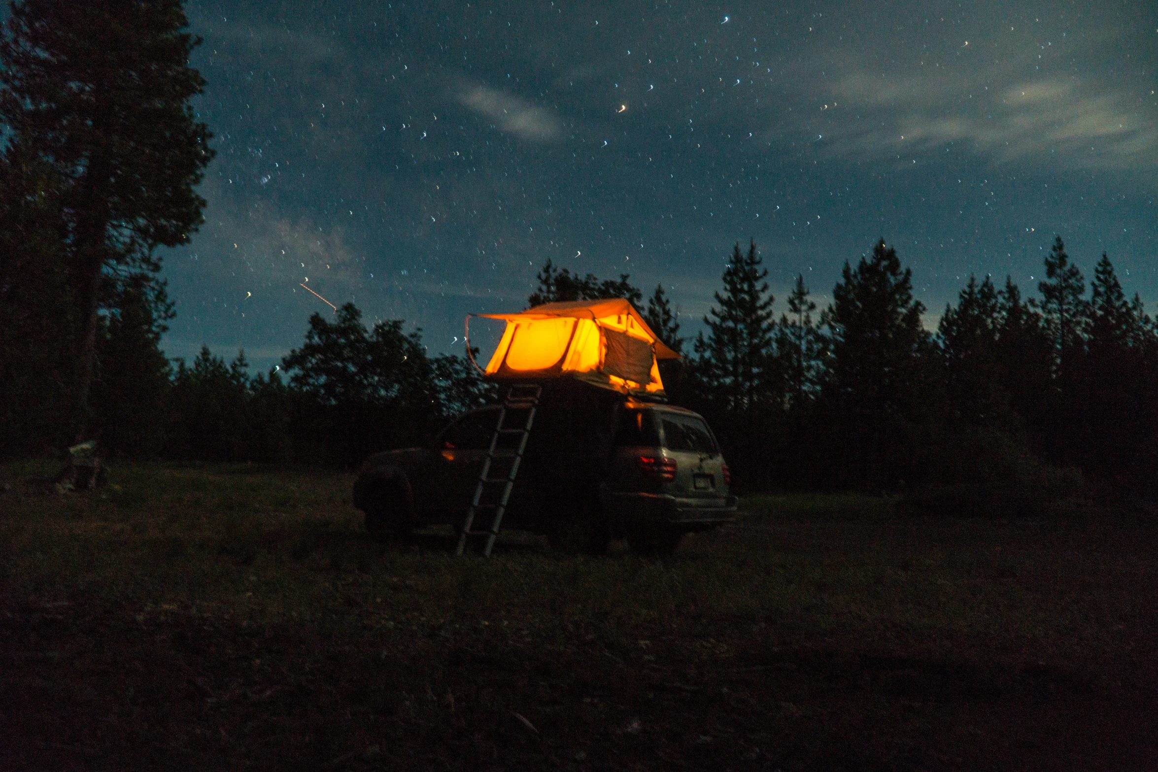 the person is sitting on a ladder near the tent