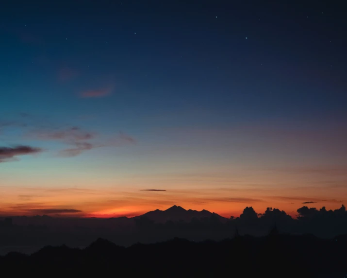 a person watching a colorful sunset with some hills