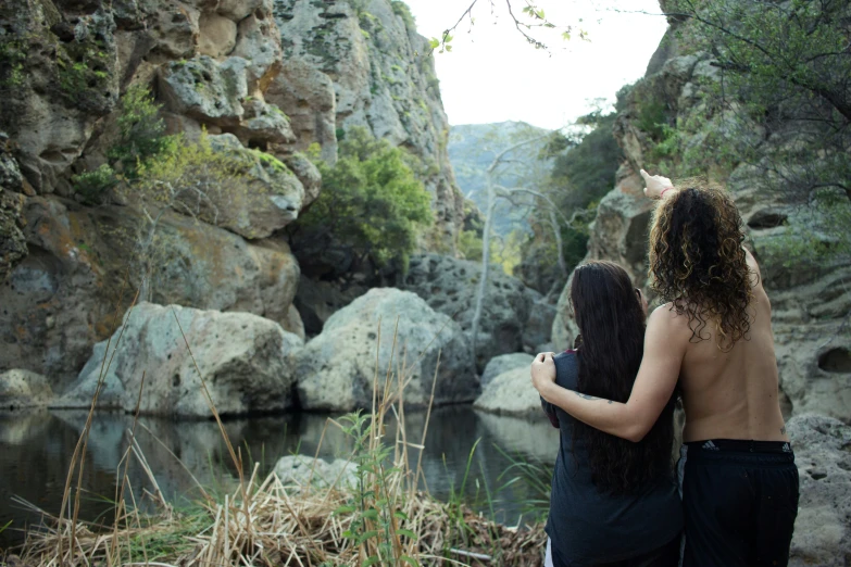 two people standing in front of a mountain lake