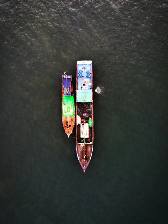 two boats with people in their seats floating in a body of water