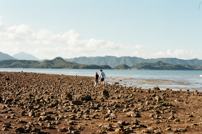 two people standing on the shore and one is holding a kite