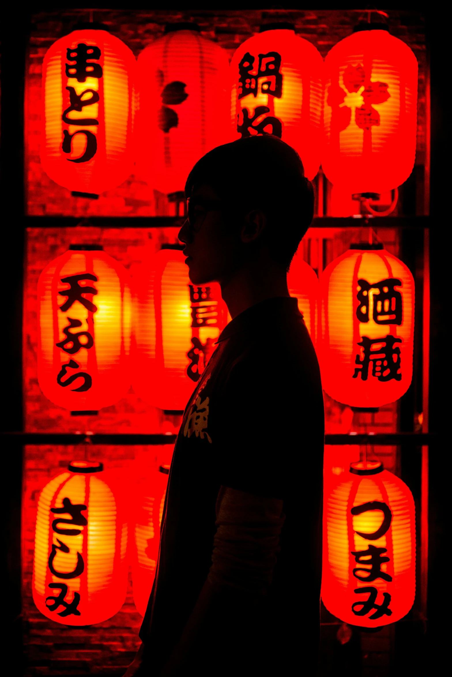 a boy stands in front of some bright red lanterns