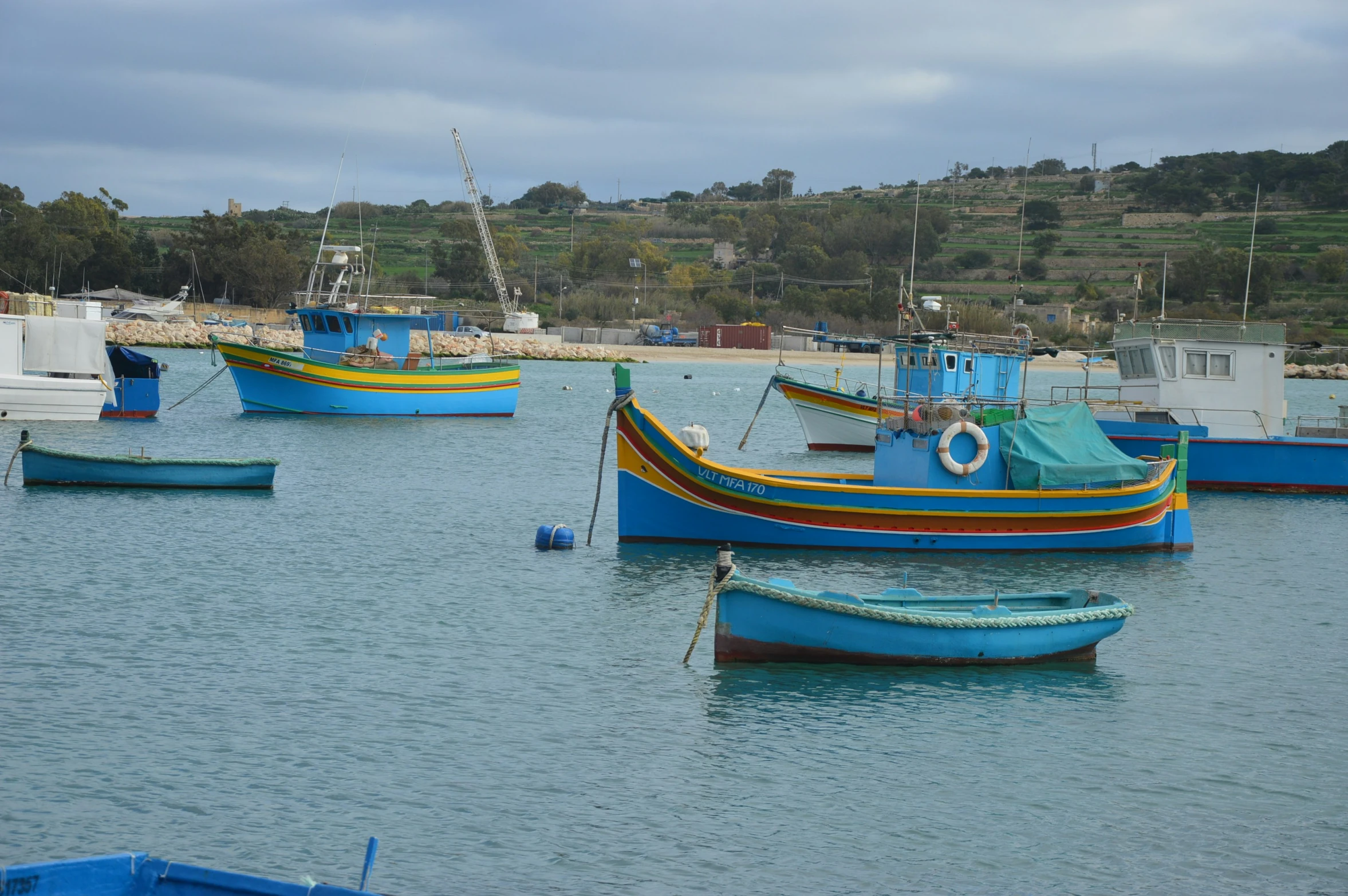 blue boats in the water near land with hills