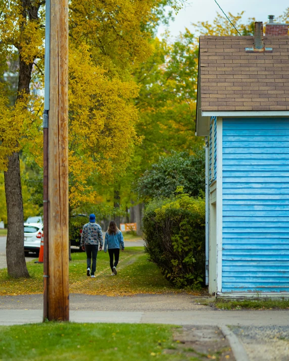 two people are walking on the sidewalk near some houses