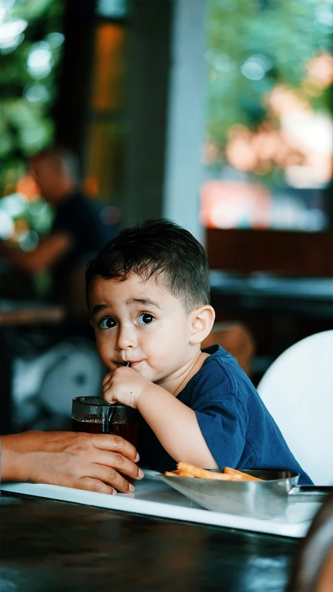 a young child drinking soing from a cup