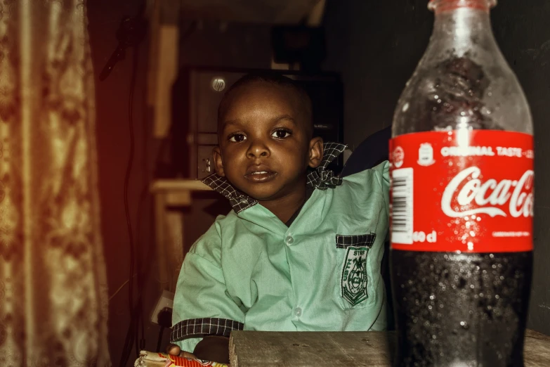 a child in blue shirt sitting next to a bottle
