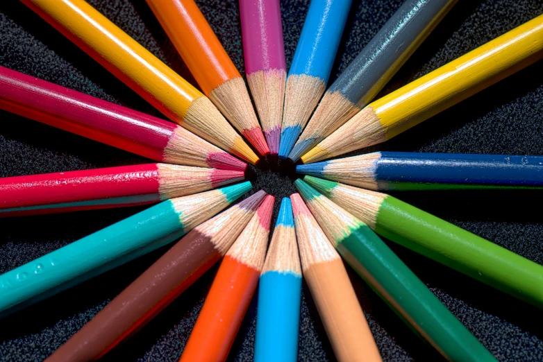 this is an arrangement of colored pencils with a black background