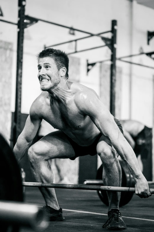 a man squats on a barbell in a crossfit gym