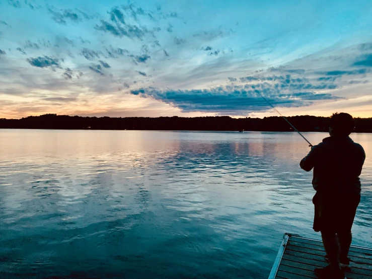 a man is standing on a dock while fishing