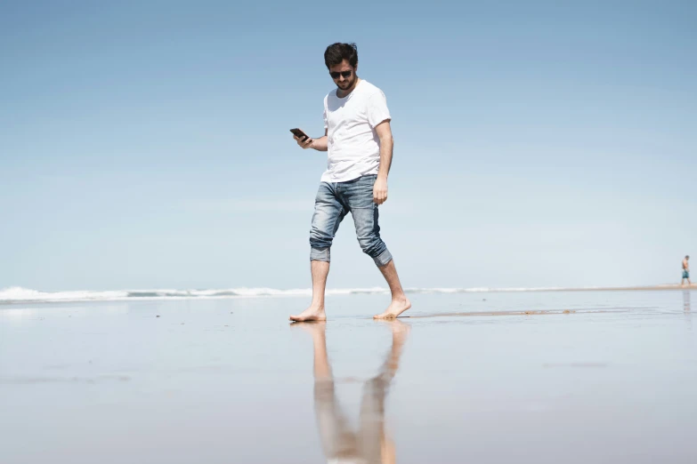 the man on the beach uses his phone