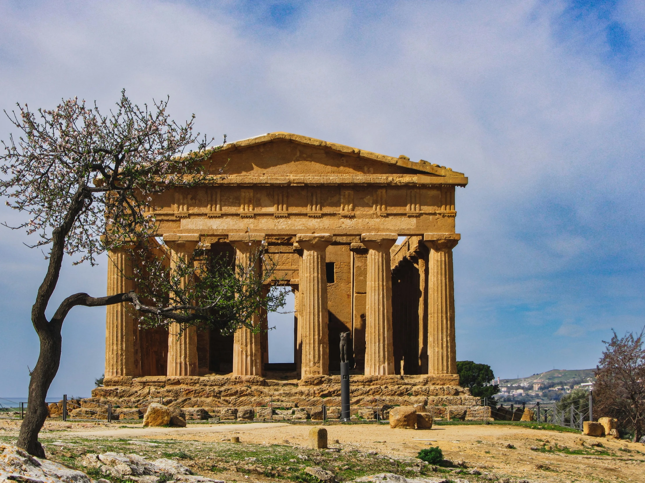 a very old building with several pillars that sits in front of a tree