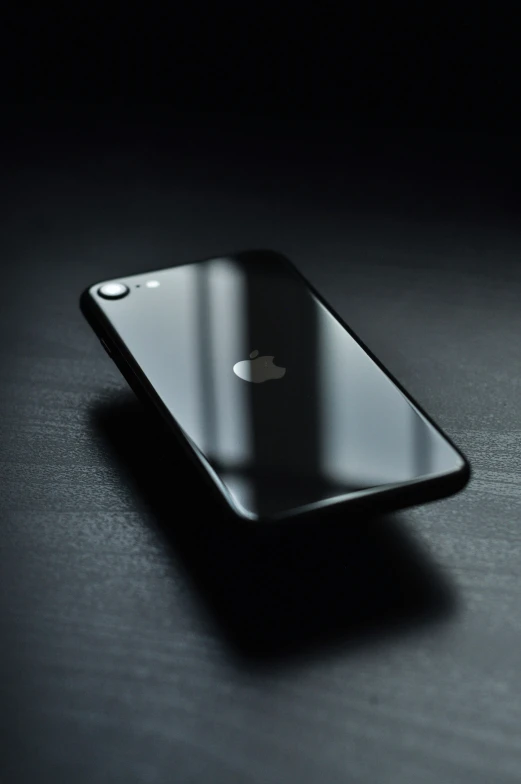 an iphone on black surface next to a black background