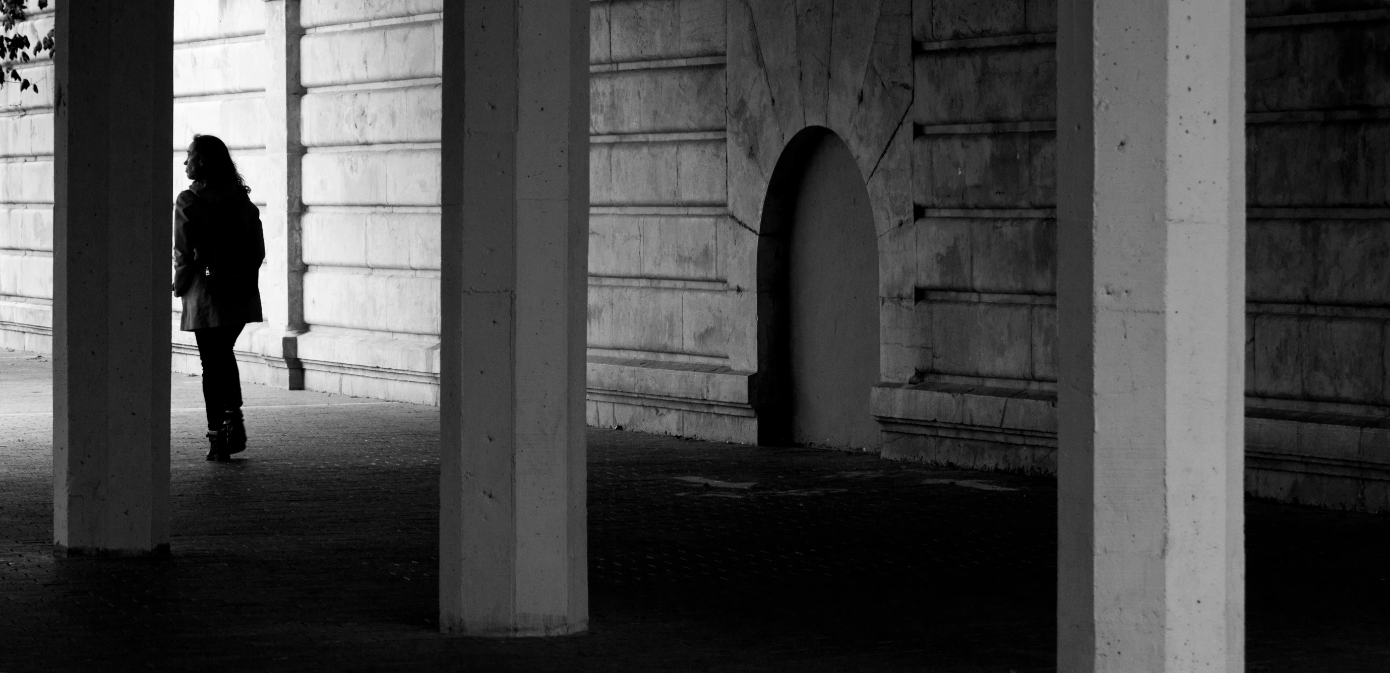 a woman walks down a long covered walkway