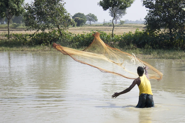 a man is wading in the river catching a large net