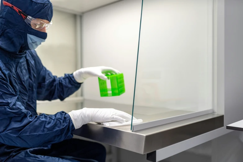 man in a protective suit cleaning a window with a green deterant