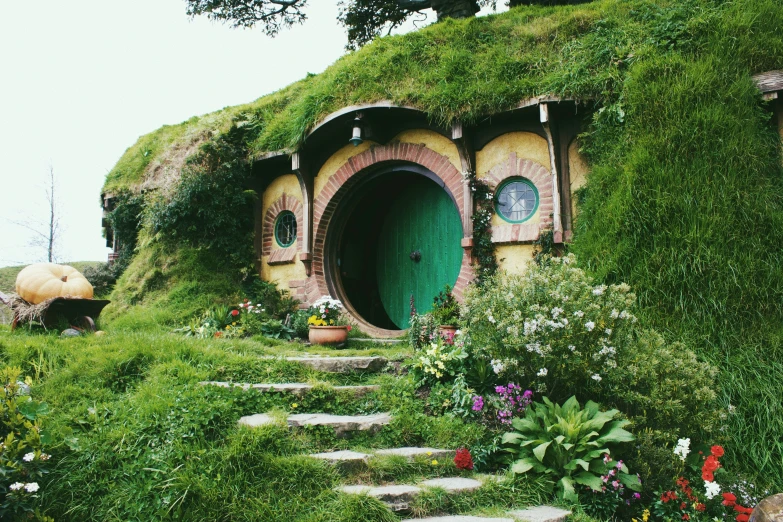 a little green house sitting in the middle of a green hillside