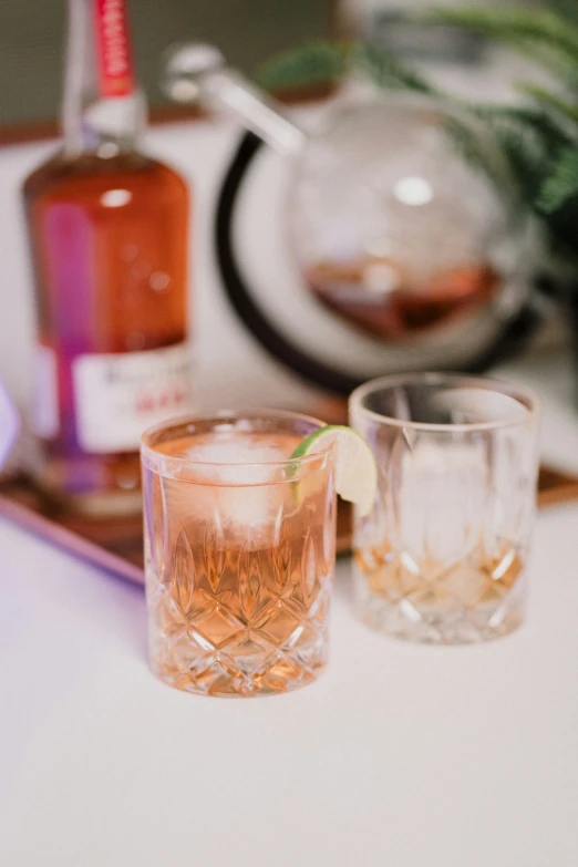 two glasses filled with whiskey sit on a bar counter