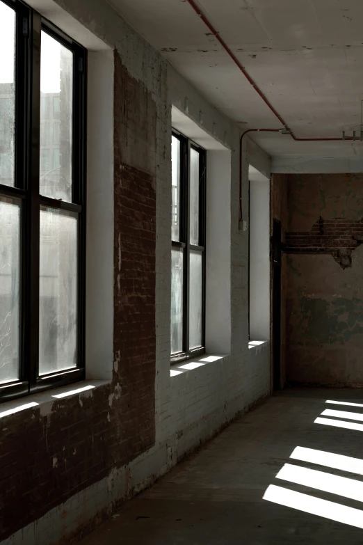 an empty hallway with windows and exposed paint